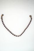 A garnet riviere necklace, the thirty three graduated oval cuts in open backed collet settings,