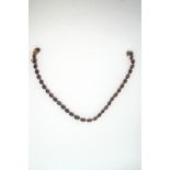 A garnet riviere necklace, the thirty three graduated oval cuts in open backed collet settings,