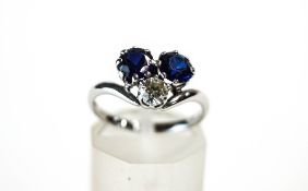A three stone sapphire and diamond ring, the white mount stamped '18ct',