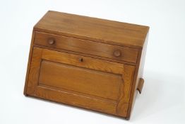An Ercol beech table top desk, with partitioned drawer over a fall front,