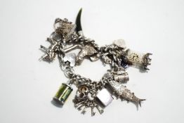 A silver bracelet, of solid curb links, with numerous charms attached,