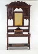 A late Victorian carved oak hall stand, with mirror back above a single drawer box and stick rack,