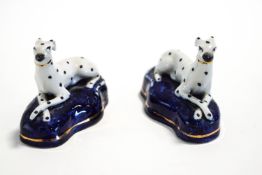 A pair of Staffordshire recumbent Dalmation dogs, on shaped bases,