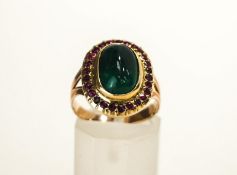 An Emerald and Ruby cluster ring, the oval cabochon enclosed by twenty six small rubies,