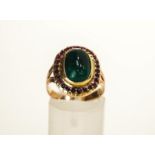 An Emerald and Ruby cluster ring, the oval cabochon enclosed by twenty six small rubies,