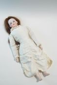 A Victorian doll with bisque head, arms and legs, cloth body and moveable joints, in later clothing,