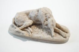 A carved marble figure of a recumbent deerhound, signed M.