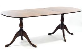 A walnut twin pedestal dining table on cabriole legs with one loose leaf,