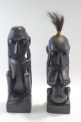 A pair of carved tribal figures of a male and female each sat on a rectangular base,