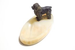 An onyx ashtray mounted with a cold painted bronze model of a sheepdog,