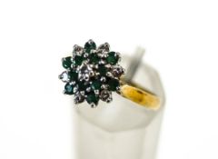 An 18 carat gold emerald and diamond cluster ring set with twelve small round cut emeralds,