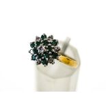 An 18 carat gold emerald and diamond cluster ring set with twelve small round cut emeralds,