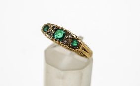 A three stone emerald 9 carat gold ring, with pairs of single cut diamonds in between,