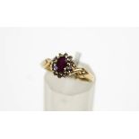 A 9 carat gold ruby and diamond cluster ring, the oval cut enclosed by twelve single cuts,