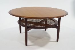 A Danish teak circular coffee table, with split cane under-tier,