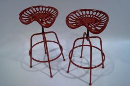 A pair of red painted cast iron adjustable tractor seat stools