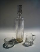 A tall glass decanter and stopper, cut with a vertical linear design,