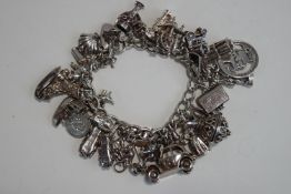 A silver bracelet, of solid curb links, to a padlock clasp, with numerous charms attached,