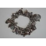 A silver bracelet, of solid curb links, to a padlock clasp, with numerous charms attached,