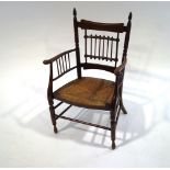 An Arts and Crafts oak and elm chair, with rush seat, spindle back and side supports,