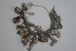 A silver bracelet, of solid curb links, to a padlock clasp, with numerous charms attached,