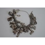 A silver bracelet, of solid curb links, to a padlock clasp, with numerous charms attached,