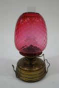A Victorian Veritas oil lamp, with brass burner and cranberry glass shade,