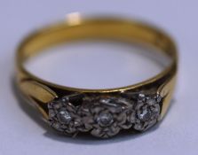 A three stone diamond ring, stamped 18ct, illusion set with small brilliant cuts, finger size P1/2,
