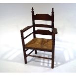 An oak and rush seat seated armchair, with ladder back, turned supports and wide arm rests,