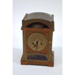 An Arts and Crafts style oak cased clock with embossed round brass dial above an inset blue glass