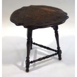 A small stained oak cricket table, with carved decoration to the top and flaps,