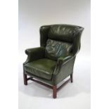 A green leather wingback armchair on square legs,