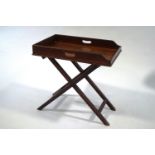 A mahogany butlers tray with pierced twin handles on folding stand,