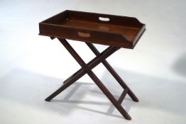 A mahogany butlers tray with pierced twin handles on folding stand,