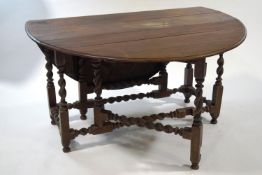 A mahogany gate leg table, the oval top on barley twist legs,