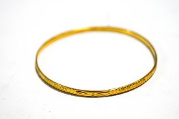 A 22 carat gold bangle, with diamond cut decoration, 3mm wide, internal diameter 6.3 cm, 12.