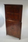 A George III oak free standing corner cabinet, in two sections,