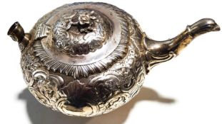 A George III silver bullet shaped teapot on foot, embossed with flowers, leaves,