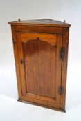 A George II oak corner cupboard, the panelled door enclosing three shaped shelves,