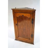 A George II oak corner cupboard, the panelled door enclosing three shaped shelves,