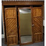 A Victorian pitch pine triple wardrobe, with unusual carved cornice and panel sides,