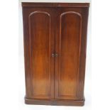 A Victorian mahogany double wardrobe with two panelled doors on plinth base,