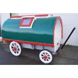 A child's wooden playhouse in the style of a Gipsy caravan, painted white, green and red,