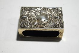 A late Victorian silver match box holder embossed with foliate scrolls, masks and a cartouche,