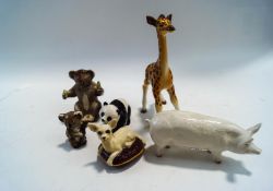Six Beswick figures of a pig, a baby giraffe, two koalas, a panda and a dog on a cushion,