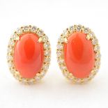 *Pair of Coral, Diamond, 14k Yellow Gold Earrings. Each centering one oval coral cabochon