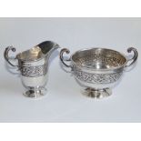 A silver two-handled sugar bowl and cream jug, decorated with bands of Celtic knot & dragon