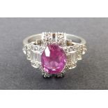 A ruby & diamond art deco style cluster ring, with central oval cut ruby set in white metal