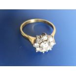 A modern diamond daisy cluster ring, the central brilliant cut stone weighing approximately 0.50