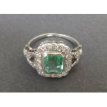 A rectangular emerald & diamond cluster ring, the emerald weighing 1.24 carats, millegrain set in '